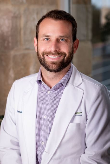 Alex Hughes, MSN, APRN, FNP-C, in a white coat